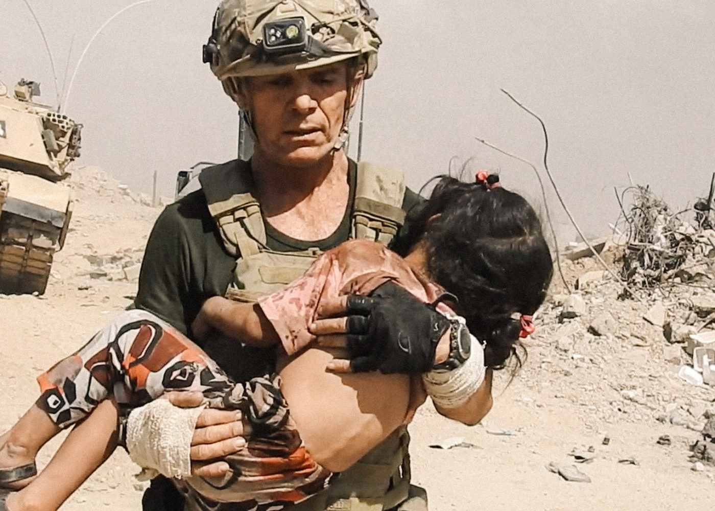 A ranger carries an injured girl to safety through rubble